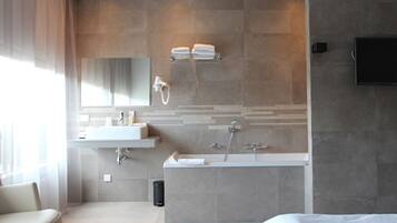 A modern bathroom with a large bathtub, a vanity with a mirror, and a towel rack.