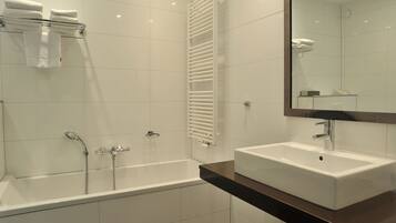 A modern bathroom with a bathtub, a shower, a white sink, and a mirror.