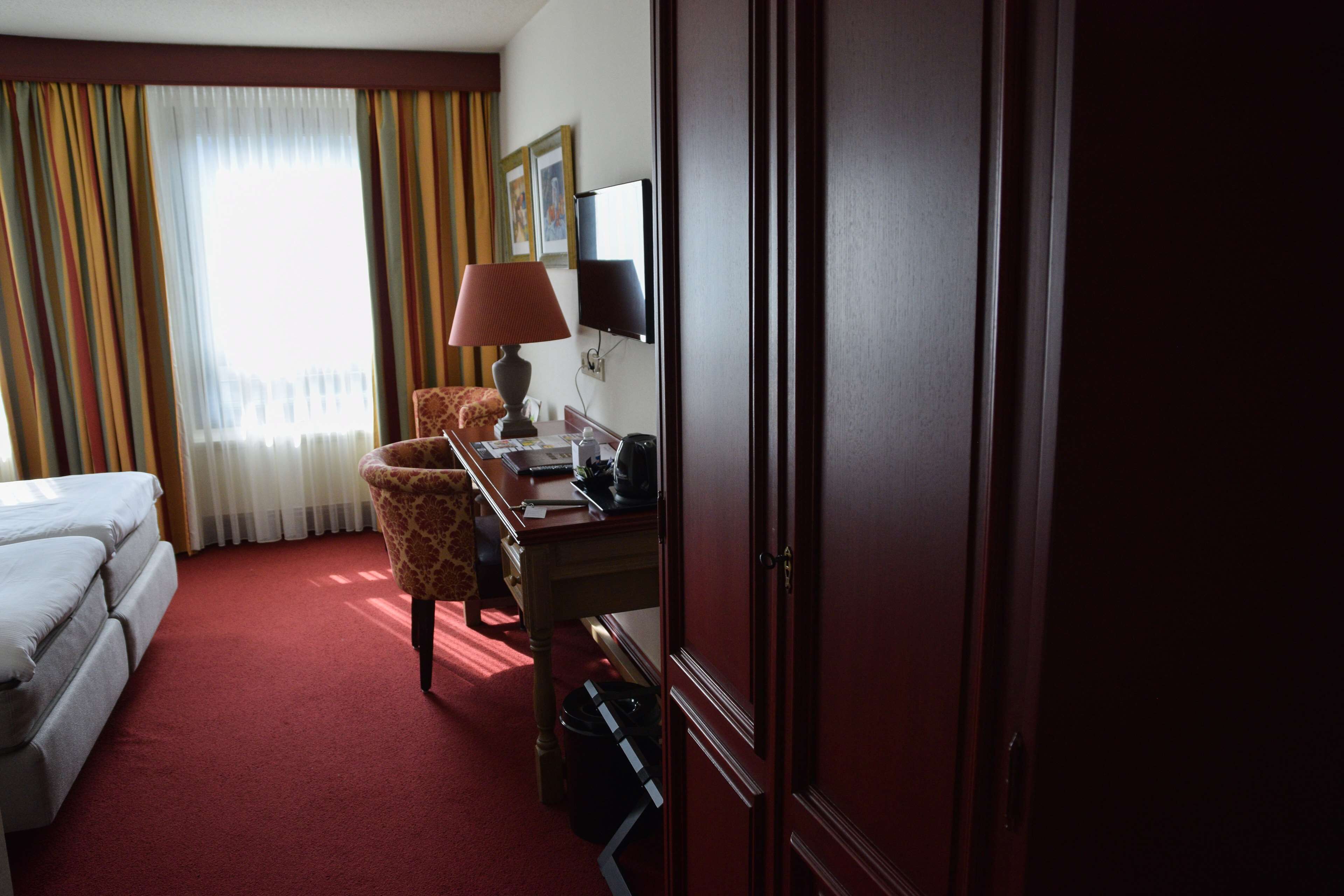 Una habitación de hotel con una cama, un escritorio con ordenador, una silla y televisión.