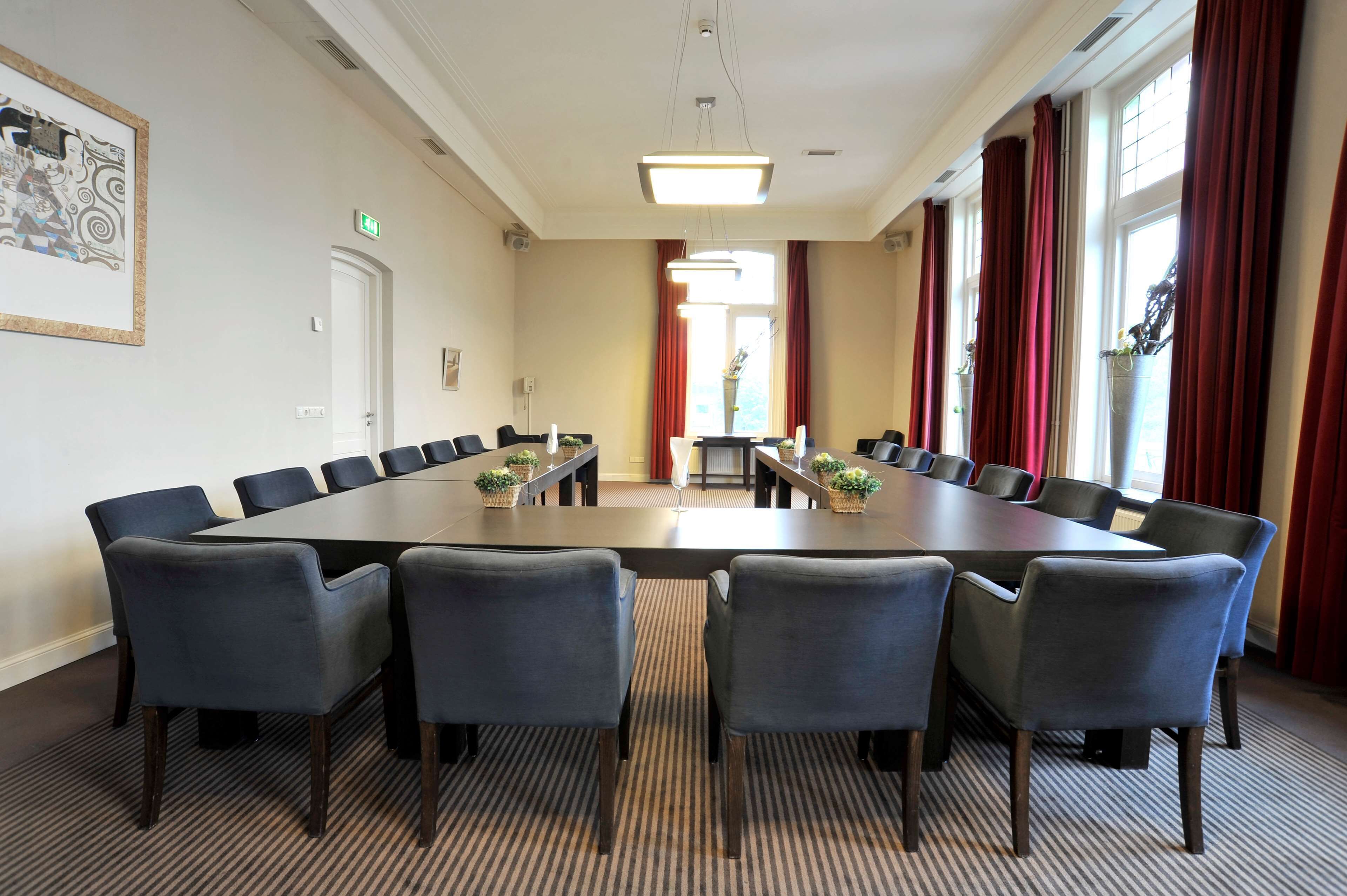 A conference room with a long table, six chairs, and a carpeted floor.