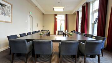 A conference room with a long table, six chairs, and a carpeted floor.