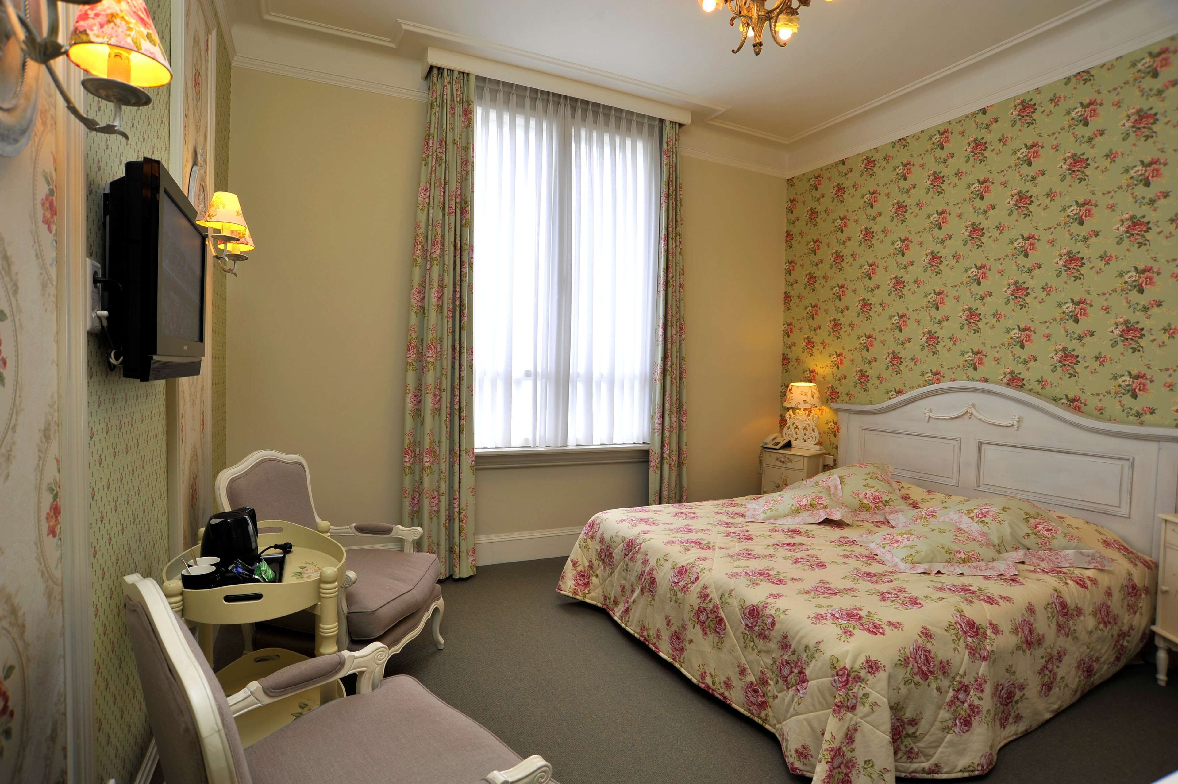 A hotel room with a bed, a chair, a small table, and a television.