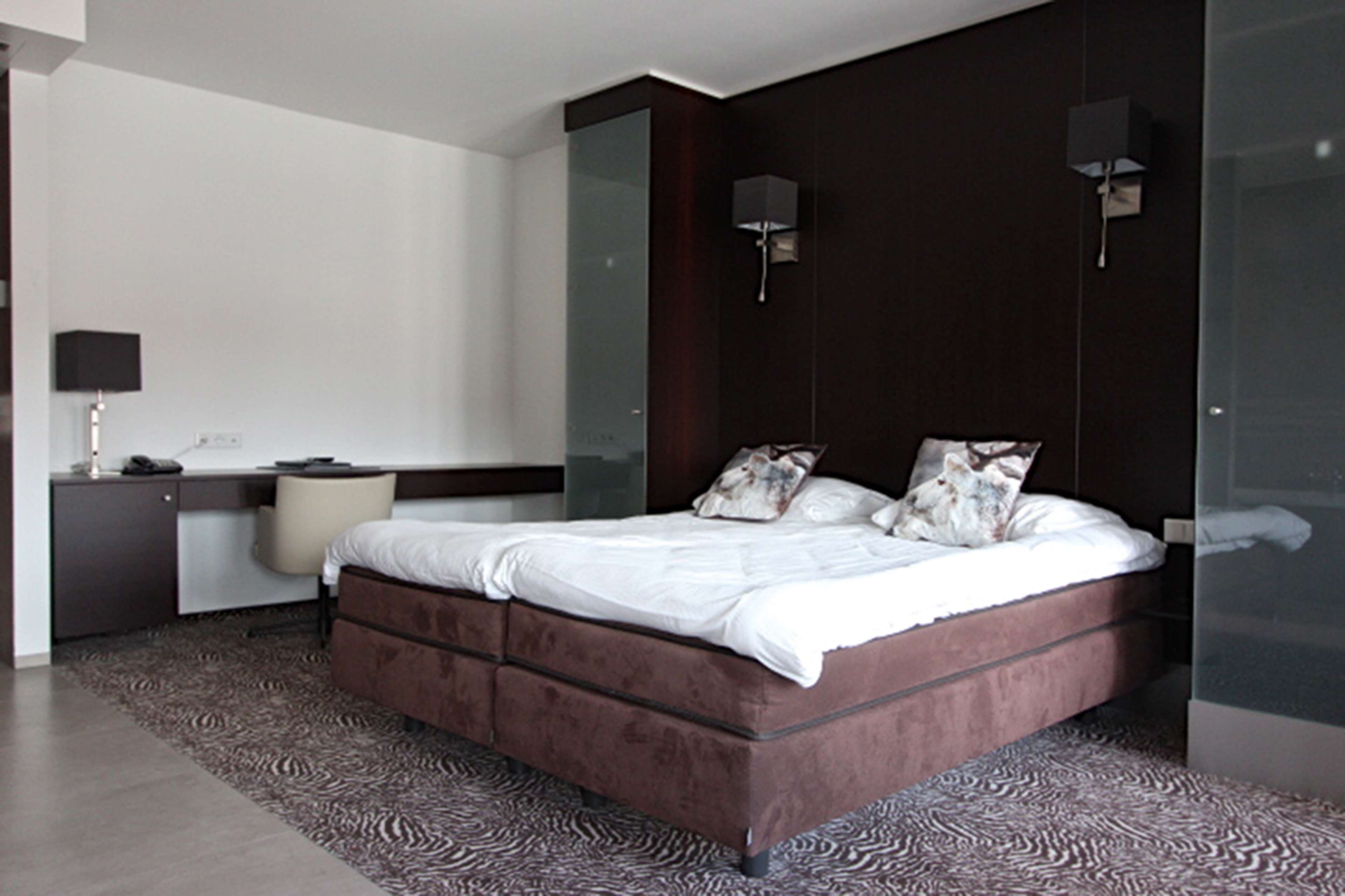 Une chambre moderne avec un grand lit, un bureau et une armoire.