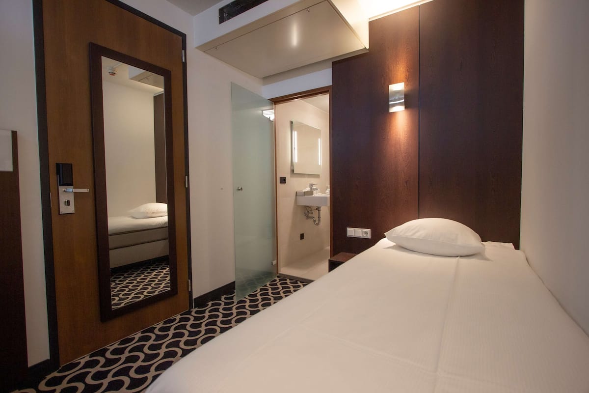 Ein Hotelzimmer mit Bett, Spiegel, Bad und Tür.