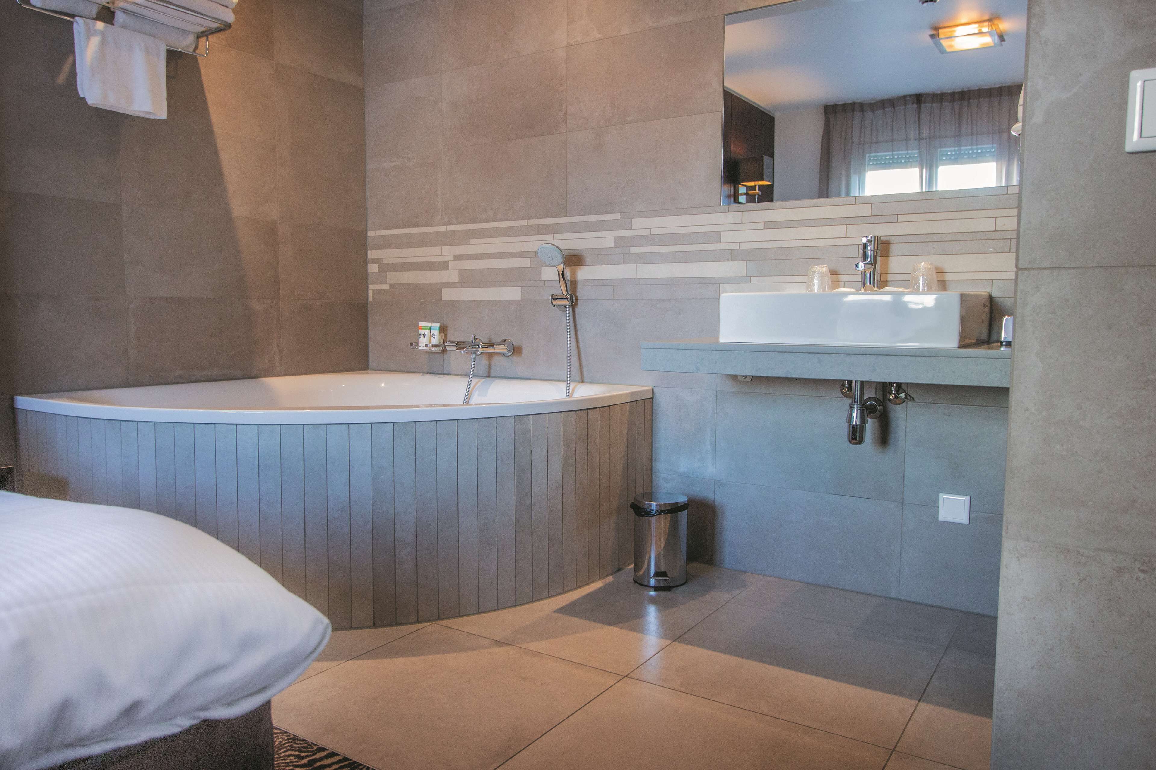 Un baño moderno con una bañera independiente, un lavamanos y un espejo.