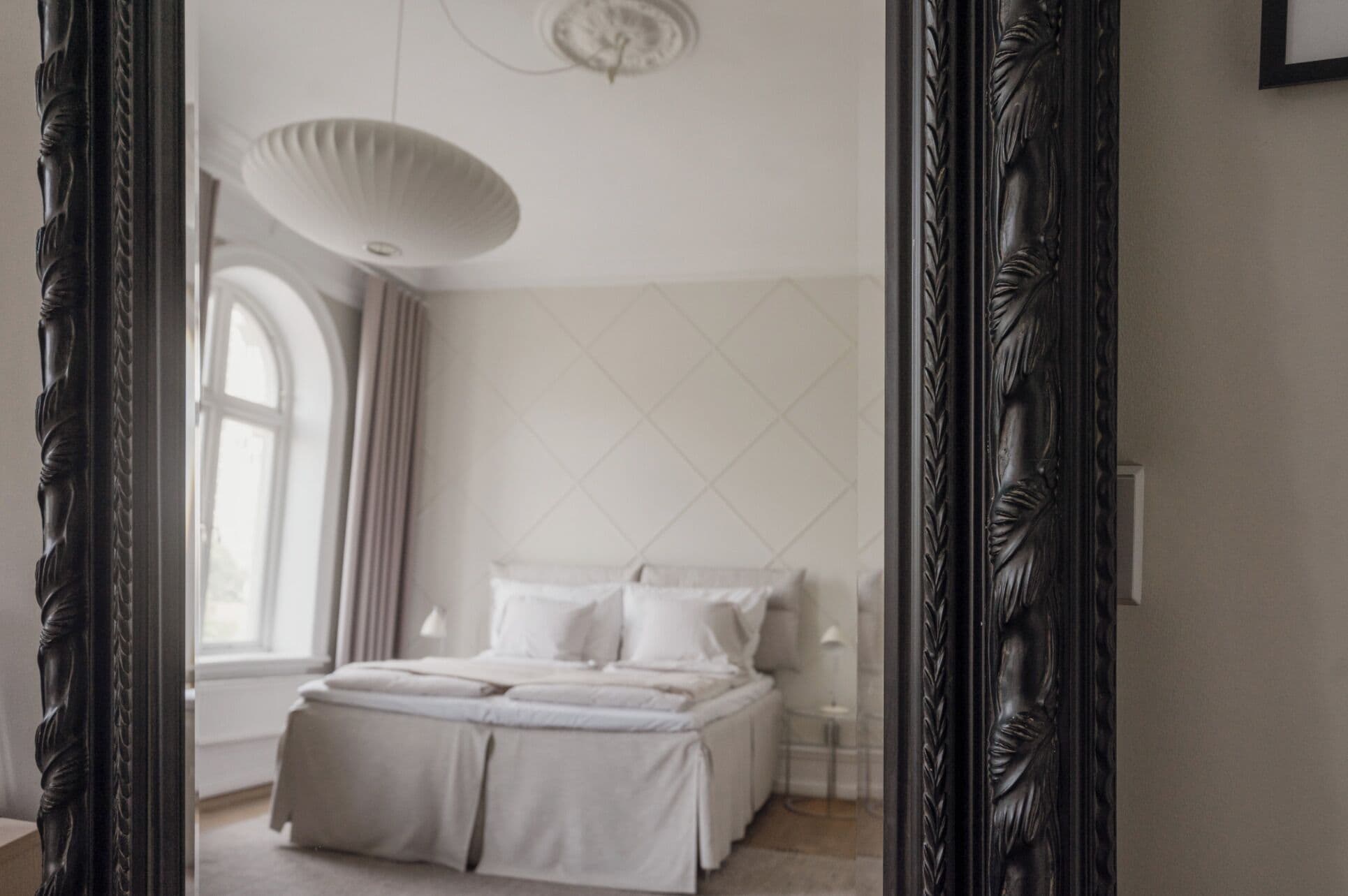 A bedroom with a bed, a window, and a mirror.