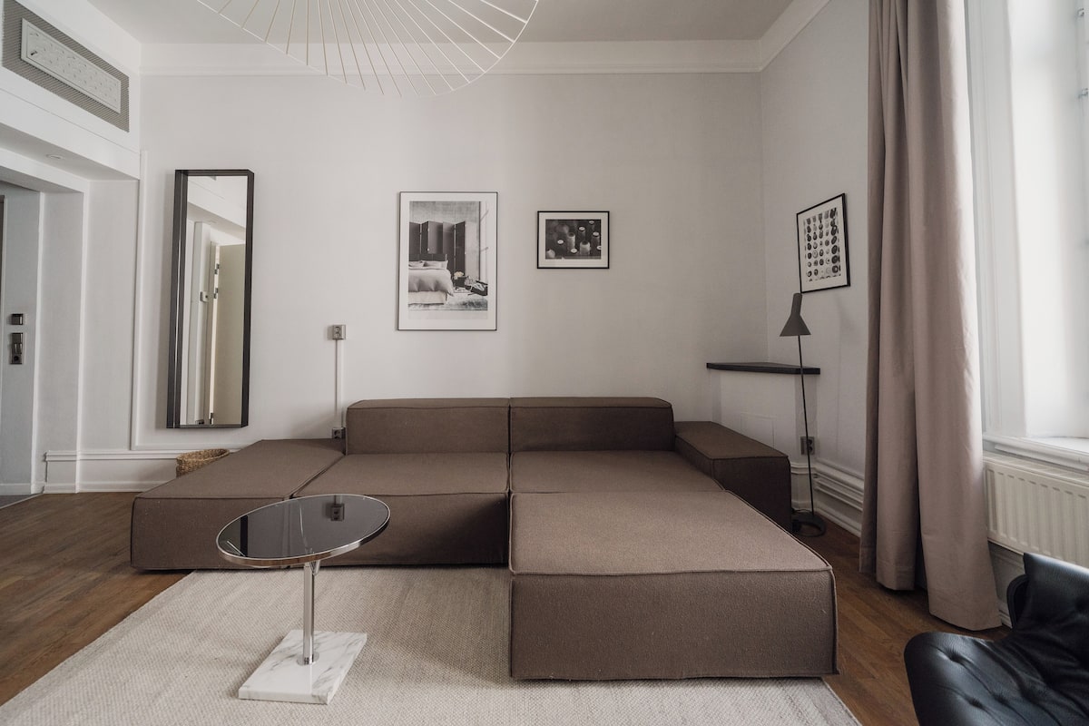 A modern living room with a sectional sofa, a small table, and artwork on the walls.