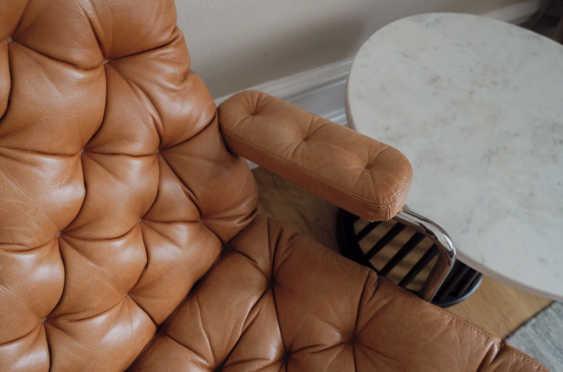 Un sillón de cuero marrón con respaldo capitonado y un reposapiés a juego.