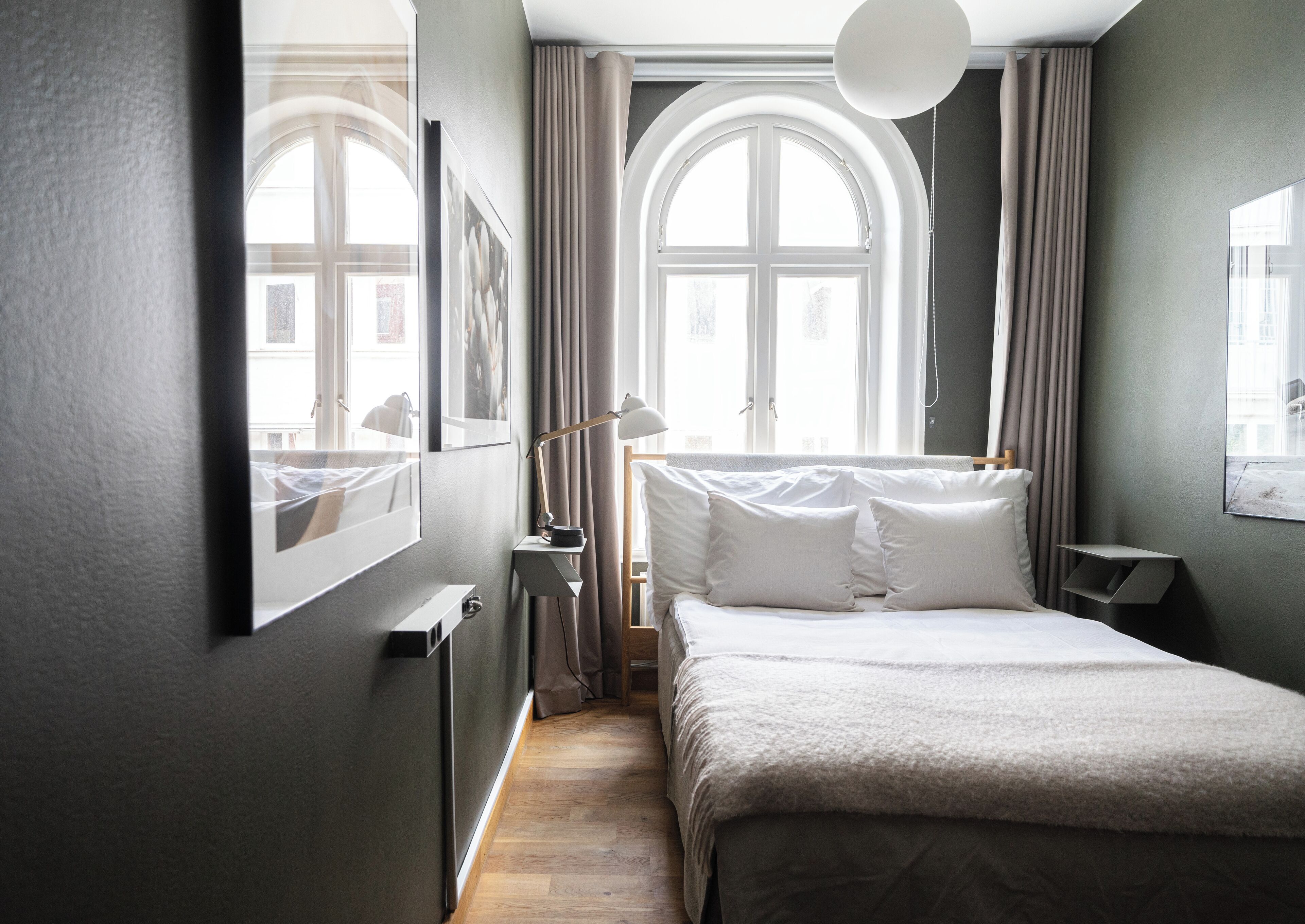 A bedroom with a bed, bedside tables, a desk, and a window with curtains.