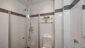 Une salle de bain moderne avec une douche à parois de verre, des carreaux blancs et une petite étagère contenant des articles de toilette.