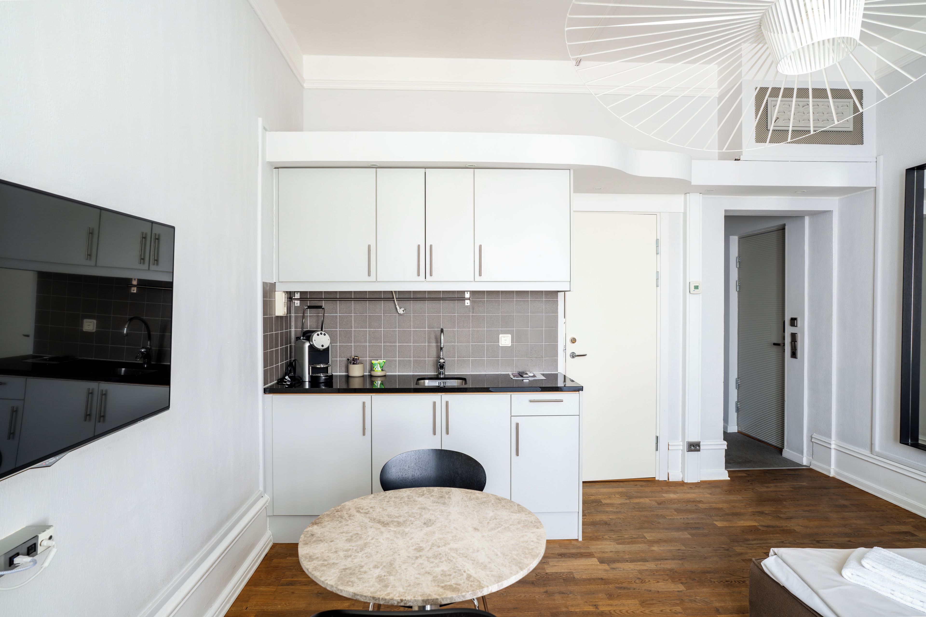 Una cocina moderna con armarios blancos, encimera negra y una mesa redonda.