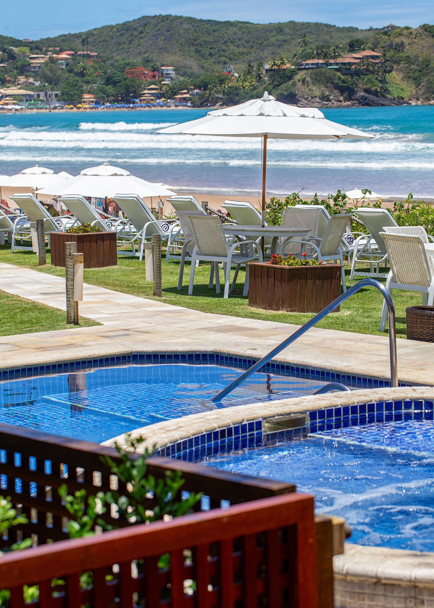 A pool area with lounge chairs and a view of the beach and ocean.