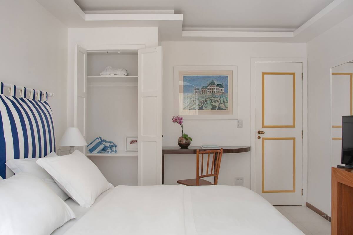 Ein Hotelzimmer mit Bett, Schreibtisch, Sessel, Fernseher und Kleiderschrank.