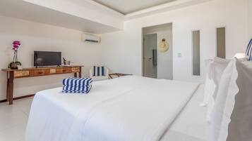 Habitación de hotel con una cama grande, un escritorio de madera con un televisor, una planta pequeña y una puerta que da a un baño.
