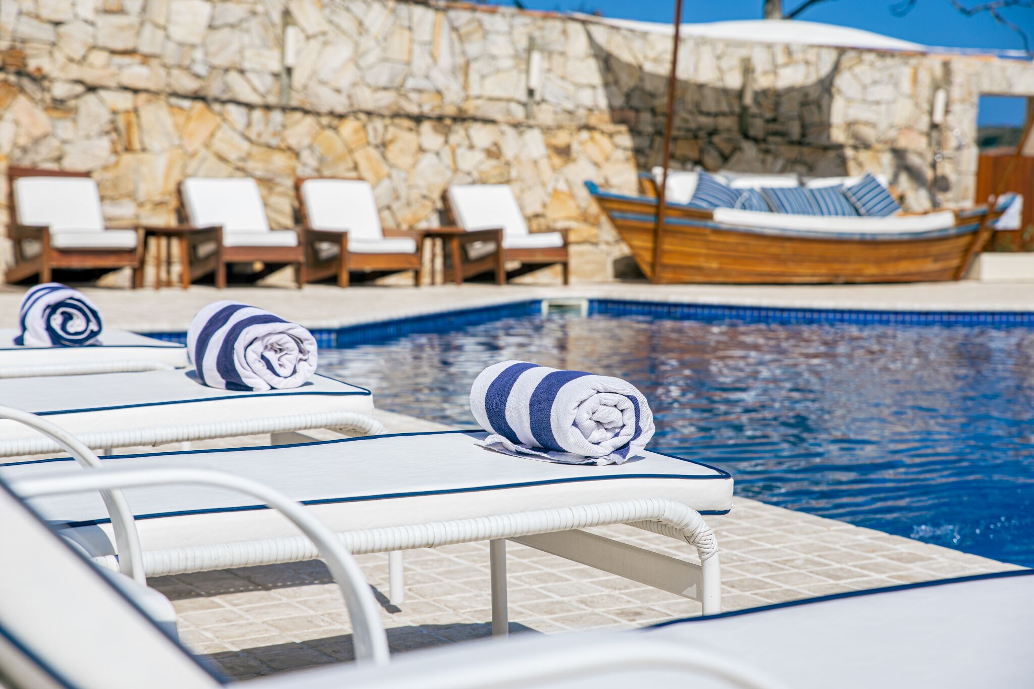 A poolside area with lounge chairs and a boat.