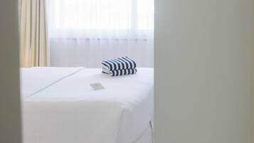 A hotel room with a bed, a window with curtains, and a white ceiling.
