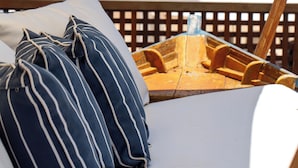 A beachside lounge with striped pillows, a wooden deck, and a view of the ocean. - Le Relais La Borie (Búzios)