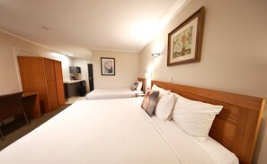 A hotel room with two beds, a desk, a wardrobe, and a painting on the wall. - Best Western Newmarket Inn & Suites (Auckland)