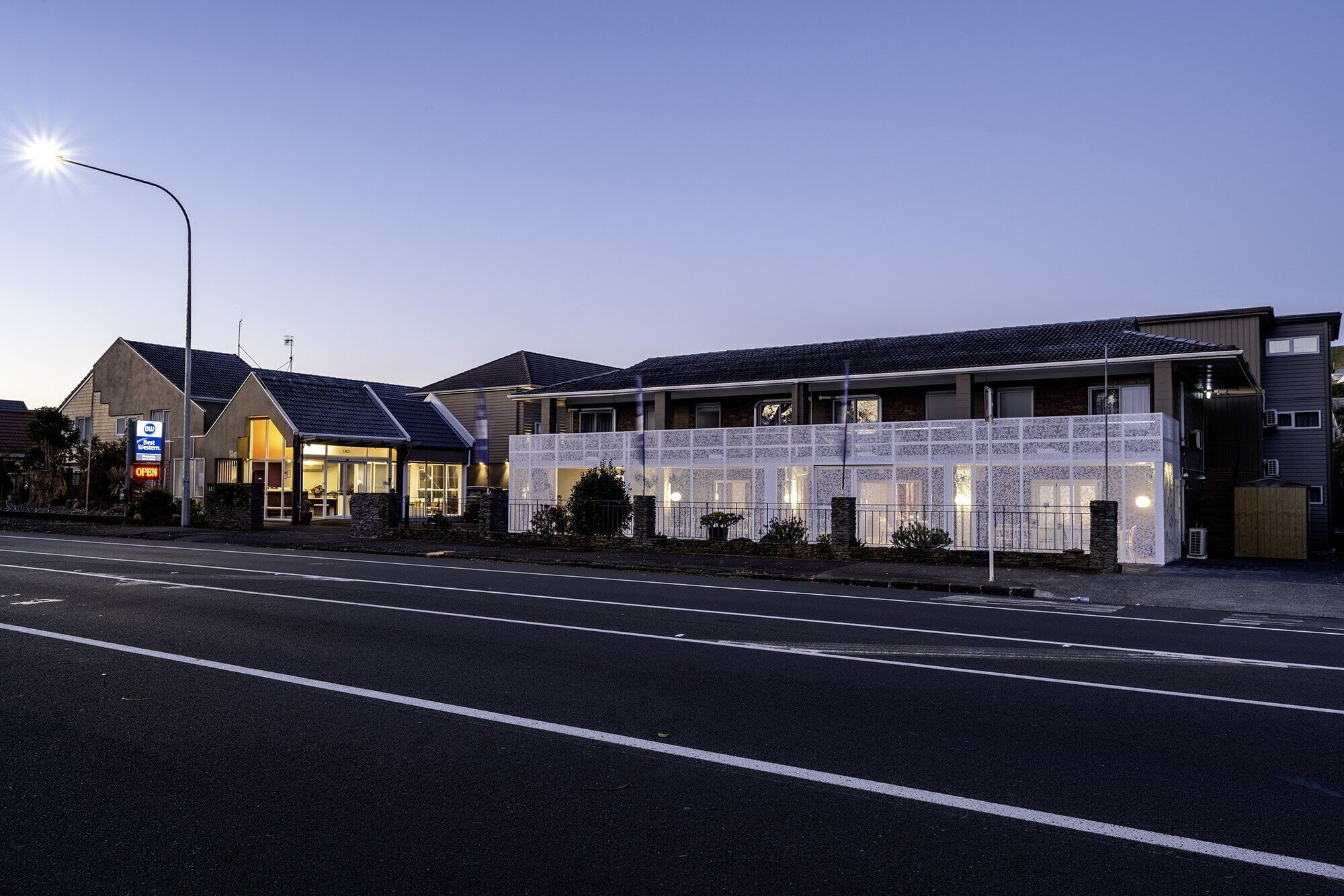 Een hotel met modern design, met een grote glazen gevel, een parkeerplaats en een straatlamp.