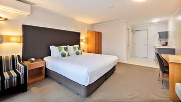 A modern hotel room with a large bed, a desk, and a chair.