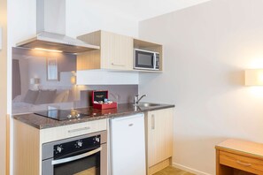 A compact kitchen with a microwave, oven, and built-in cabinets. - Best Western Newmarket Inn & Suites (Auckland)