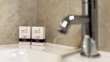 Deux bonnets de douche sur un lavabo blanc, avec un mur en marbre en arrière-plan.
