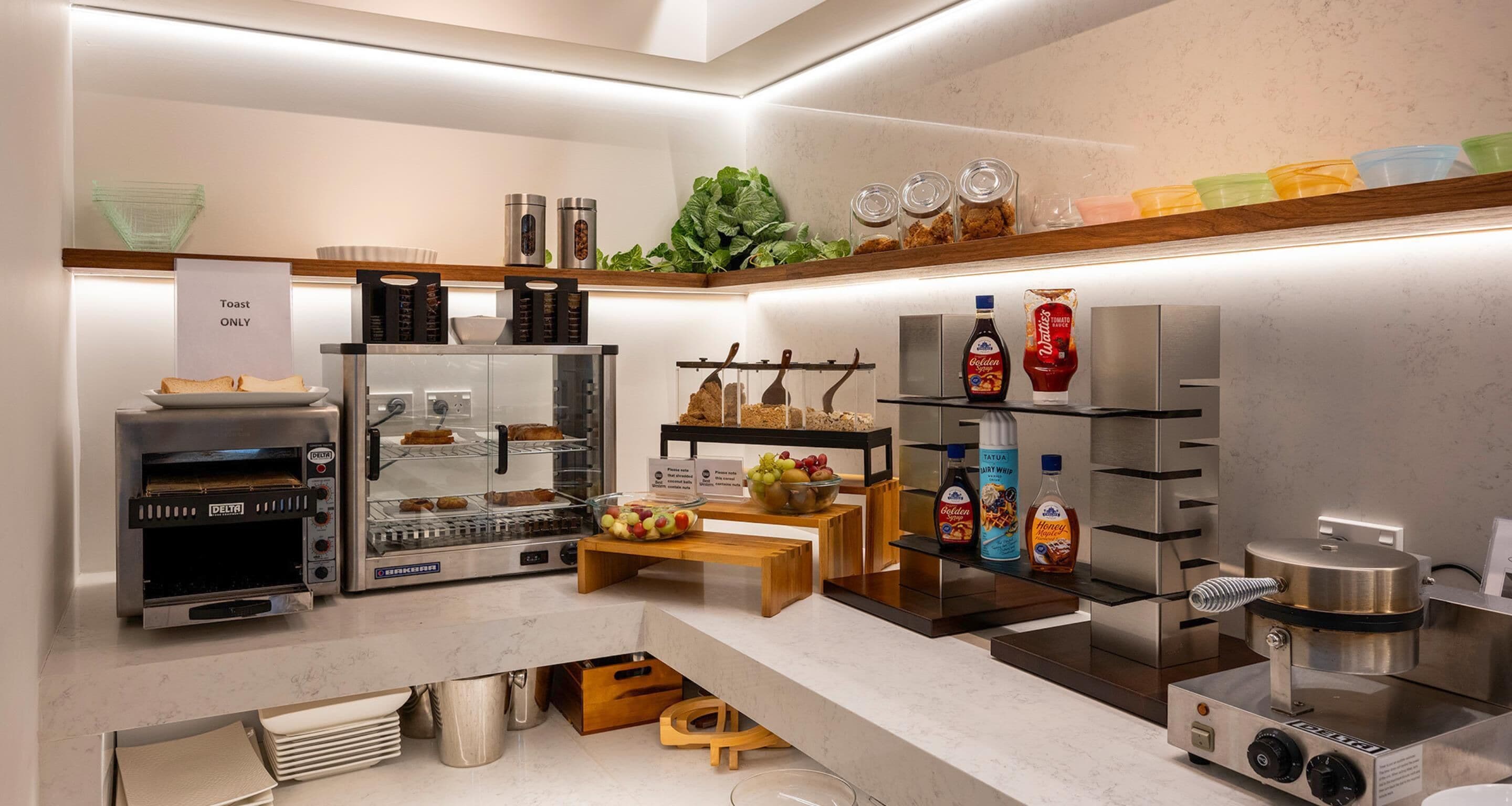 A modern kitchen with a Delta toaster oven, a stainless steel refrigerator, and a coffee machine.