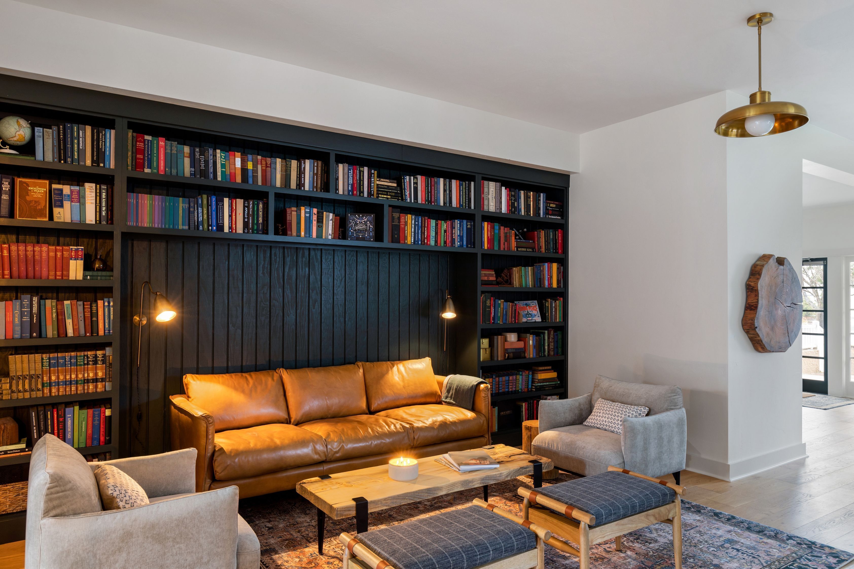 A modern living room with a leather sofa, a coffee table, and a bookshelf filled with books.
