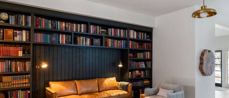 A modern living room with a leather sofa, a coffee table, and a bookshelf filled with books.