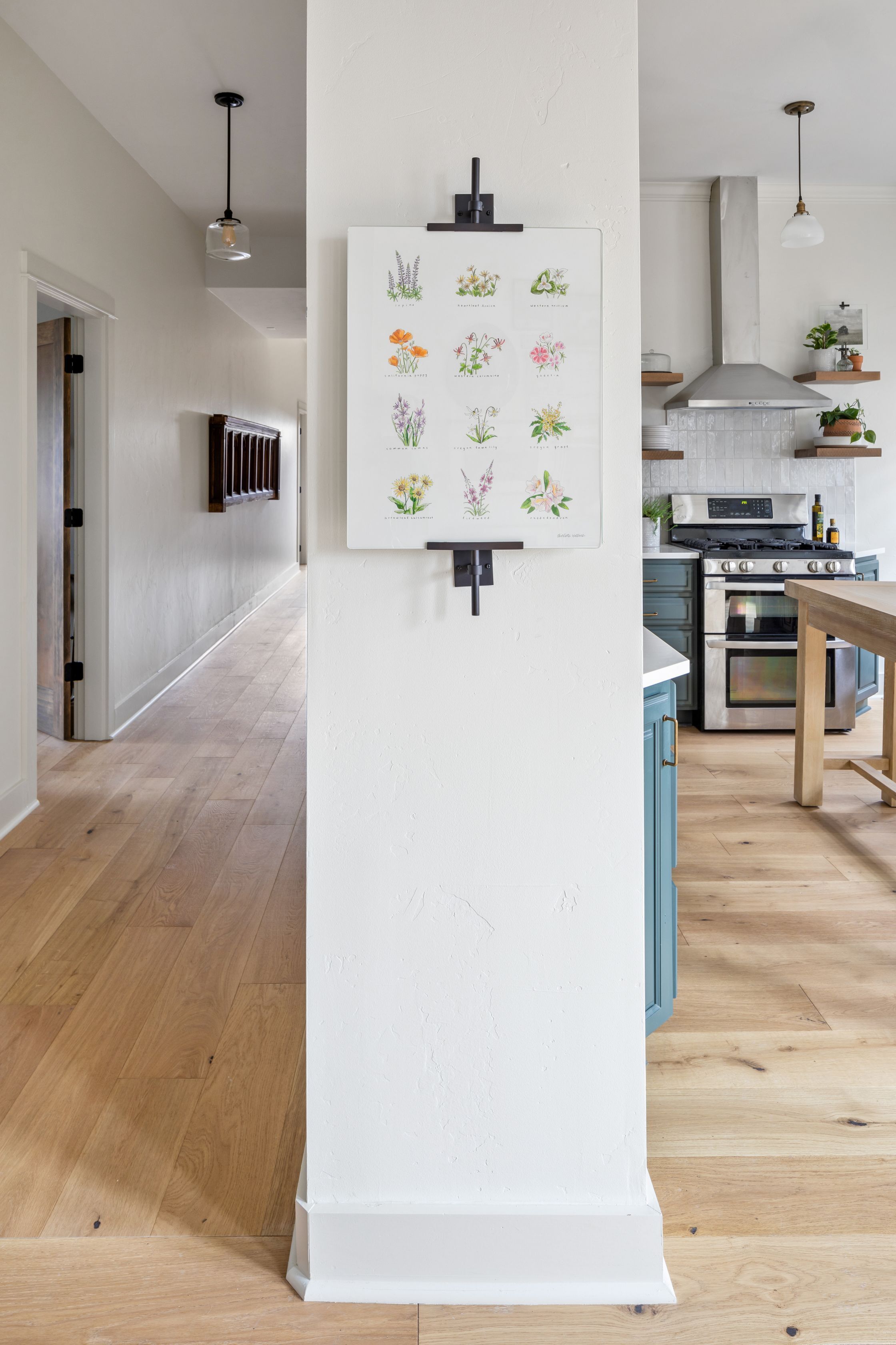 Een moderne keuken met witte kasten, een houten aanrecht en een hanglamp.
