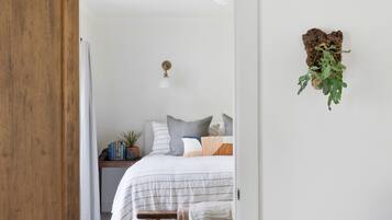 A bedroom with a bed, bedside table, and a hanging plant.