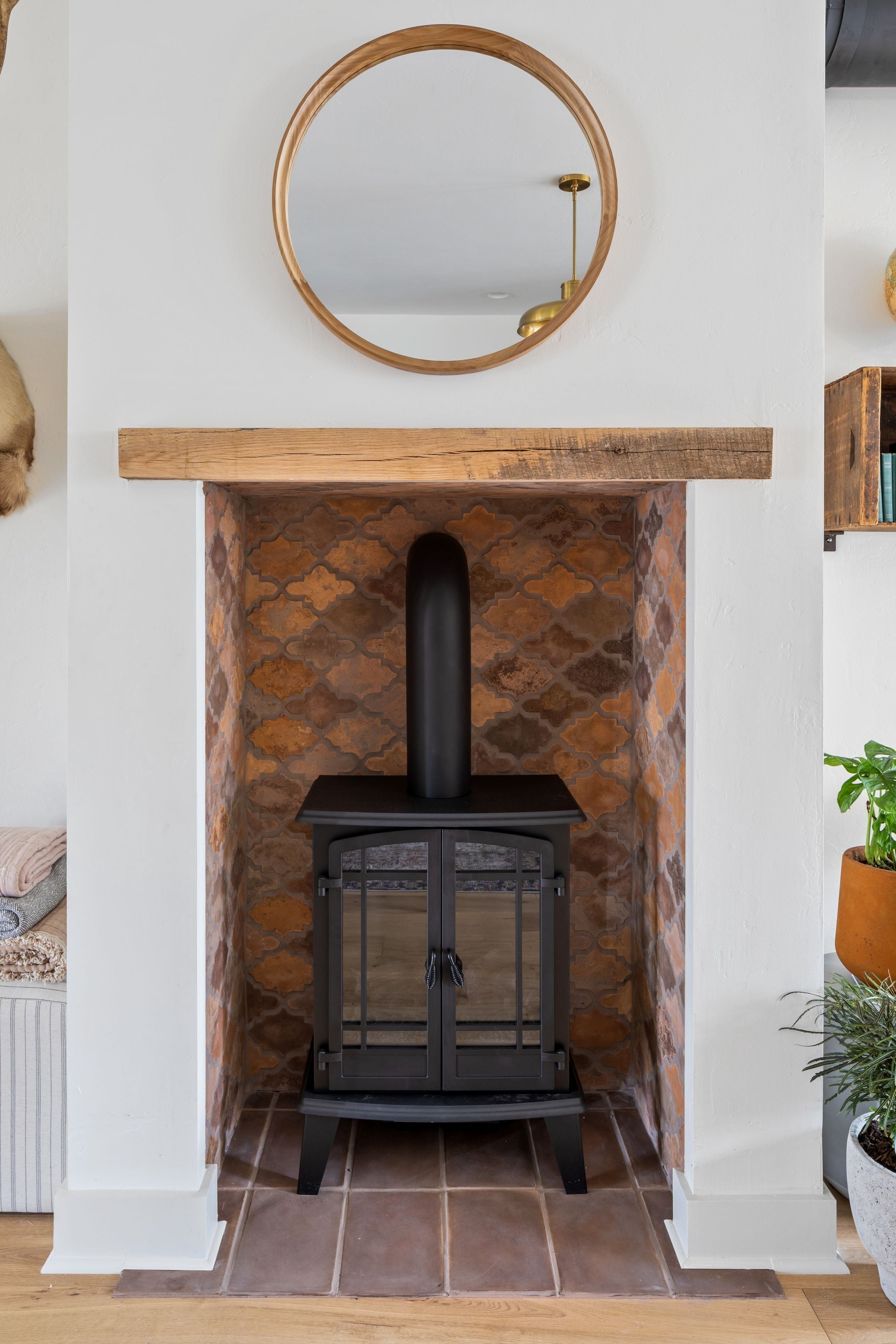 A fireplace with a stone surround, a black wood-burning stove, and a wooden mantel above it.