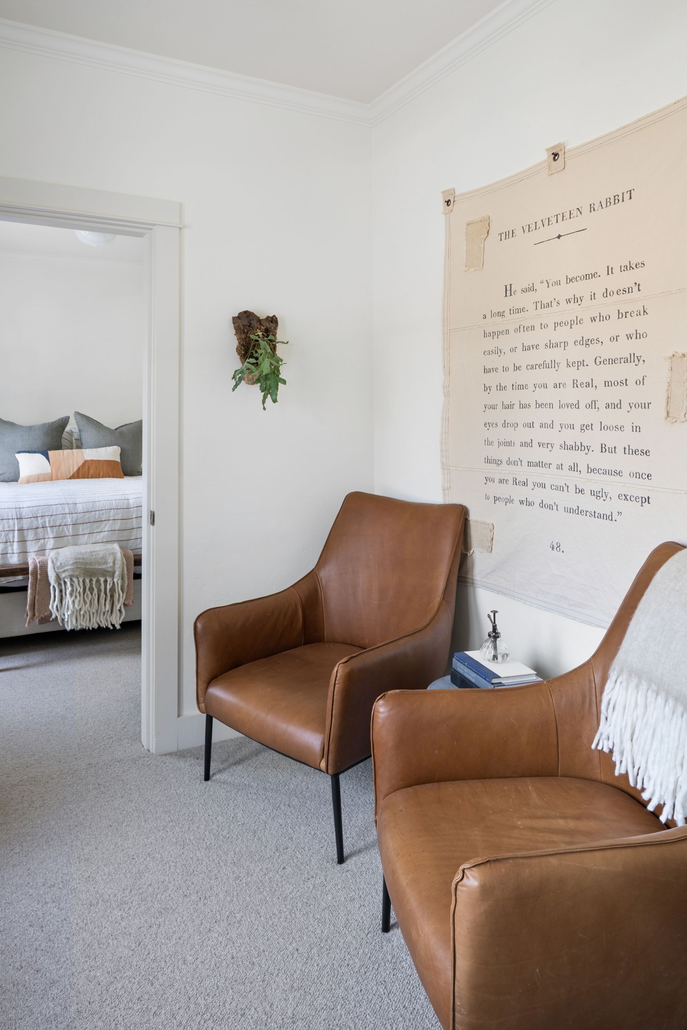 A bedroom with a large bed, a brown leather chair, and a wall-mounted book titled "The Velvet Teen Rabbit".