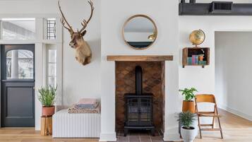 A living room with a stone fireplace, a mounted deer head, a round mirror, and a globe on a shelf.