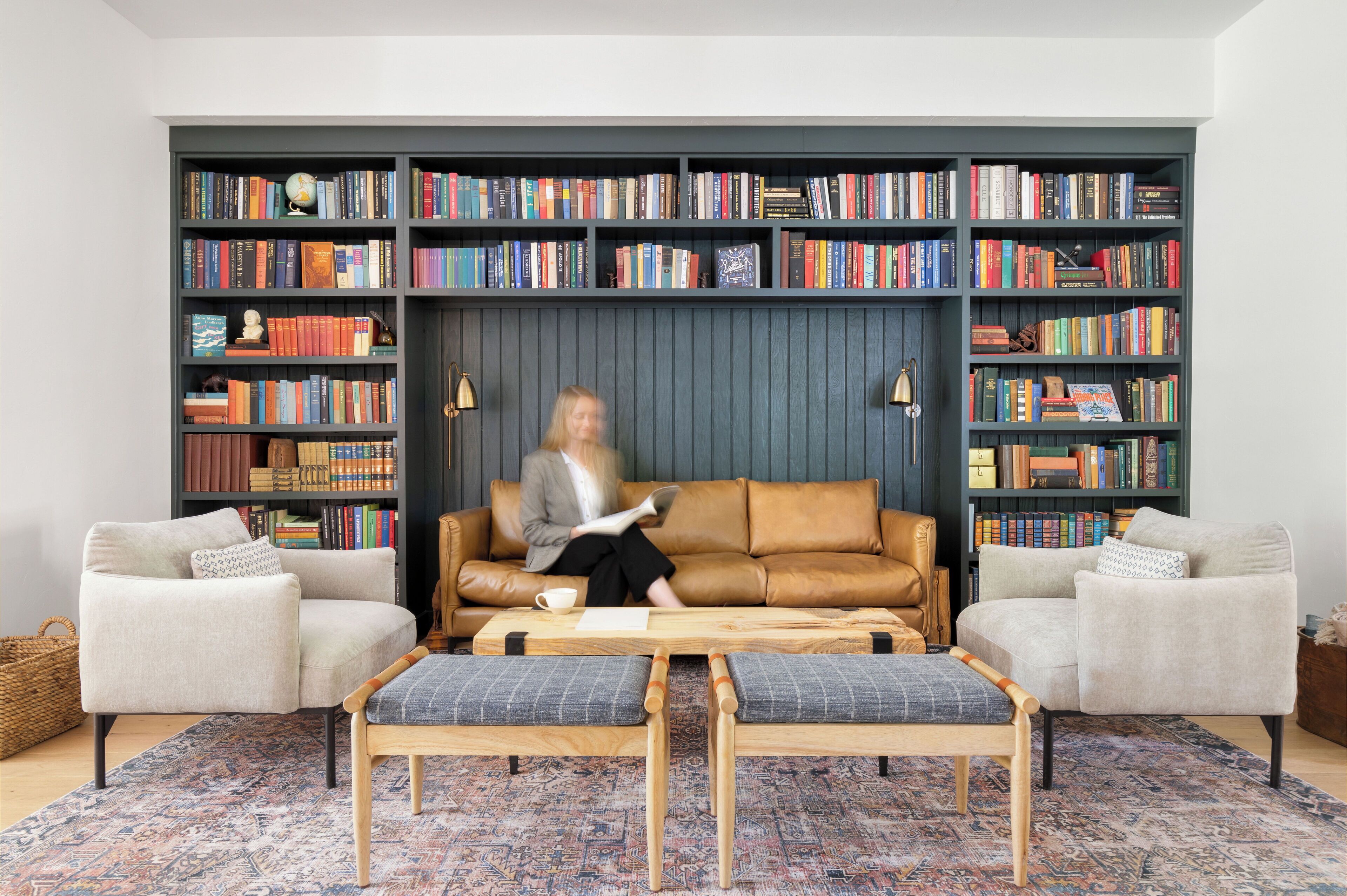 Un salon comprenant un canapé, deux fauteuils, une table basse et une bibliothèque remplie de livres.