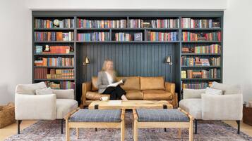 A living room with a sofa, two armchairs, a coffee table, and a bookshelf filled with books.
