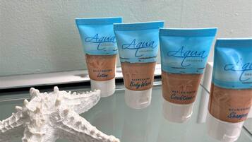 Four Aqua Organics body wash and conditioner tubes on a glass surface with a white starfish decoration.