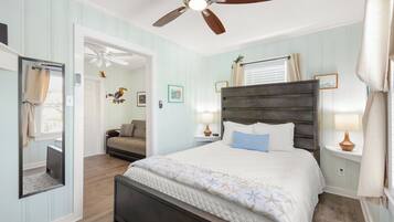 A bedroom with a bed, a ceiling fan, a nightstand, and a mirror.
