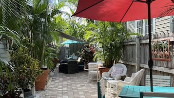 A paved patio with outdoor furniture and potted plants.
