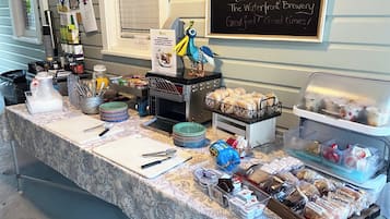 Un bufé de desayuno con diversos alimentos y un menú en pizarra que ofrece opciones como 'Martins', 'Hot Tin Roof' y 'B.O.S. Fishwagon'.