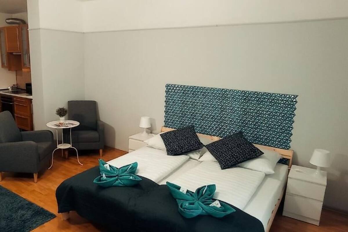 A hotel room with a bed, a desk, a chair, and a small table.