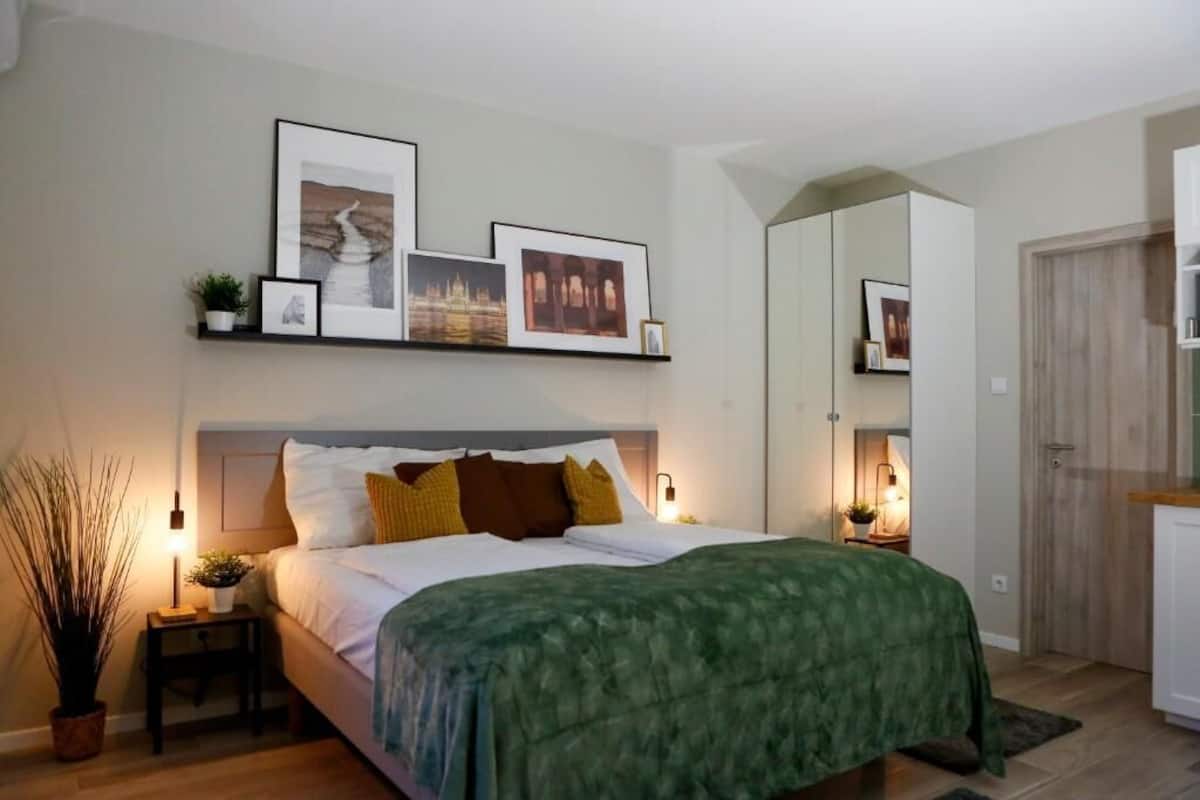 A bedroom with a bed, bedside tables, a mirror, and framed pictures on the wall.