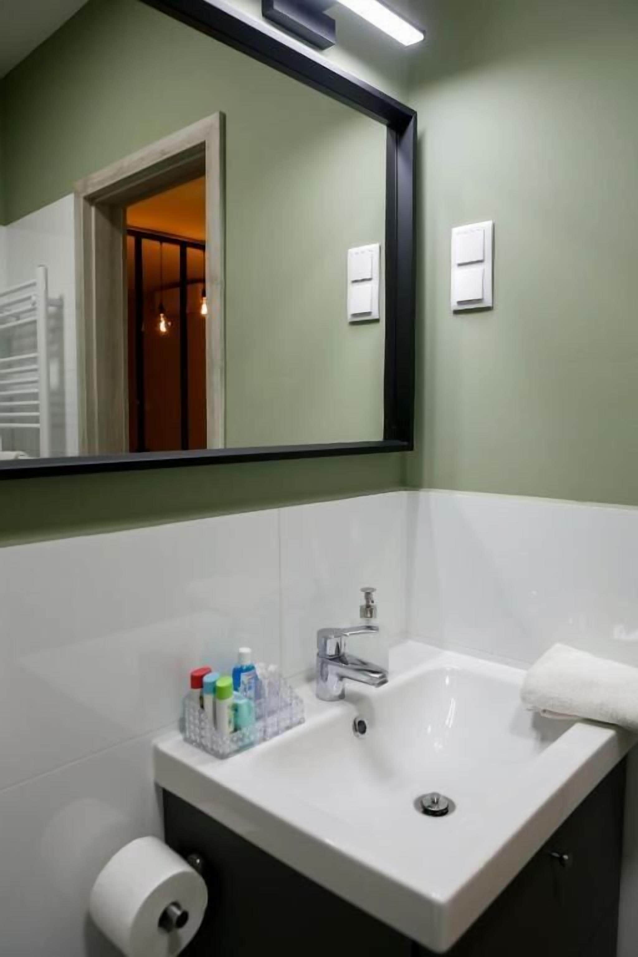 Une salle de bain avec un lavabo blanc, un miroir et un porte-serviettes.