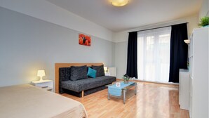 Ein modernes Hotelzimmer mit Bett, Sofa, kleinem Tisch und einem Fenster mit Vorhängen.