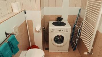Une petite salle de bain comprenant des toilettes, un lave-linge et un radiateur.