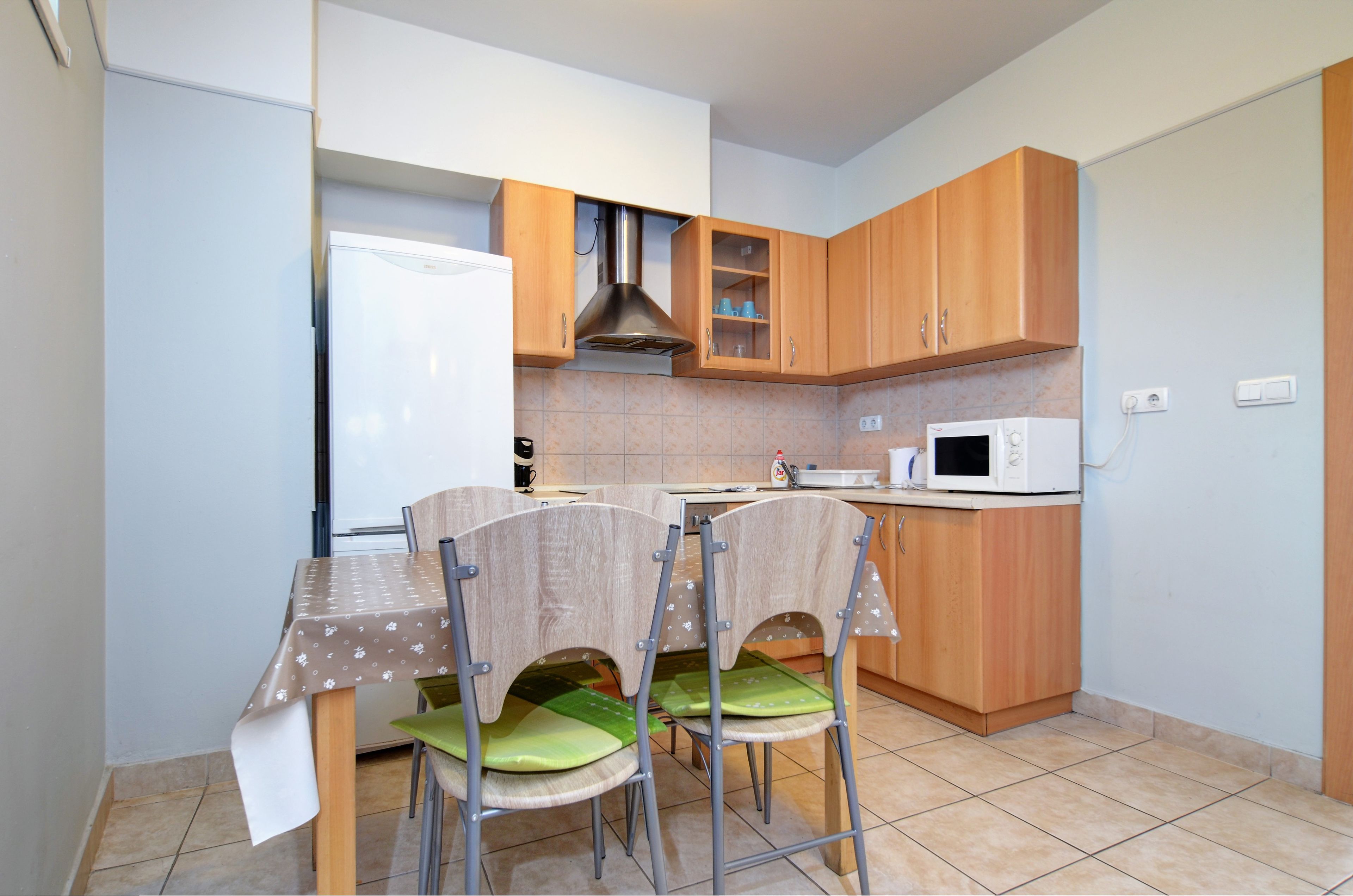 A compact kitchen with wooden cabinets, a microwave, and a table with chairs.