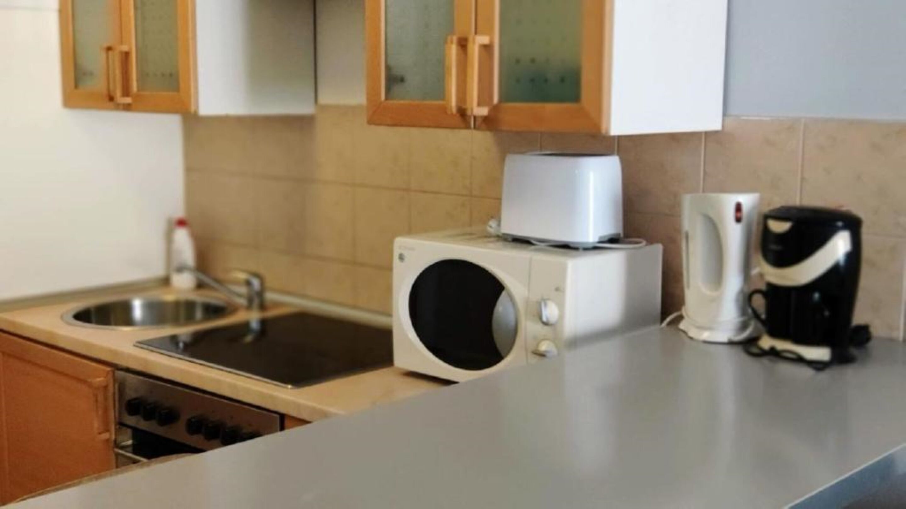 A kitchen with a microwave, a coffee maker, and a sink.