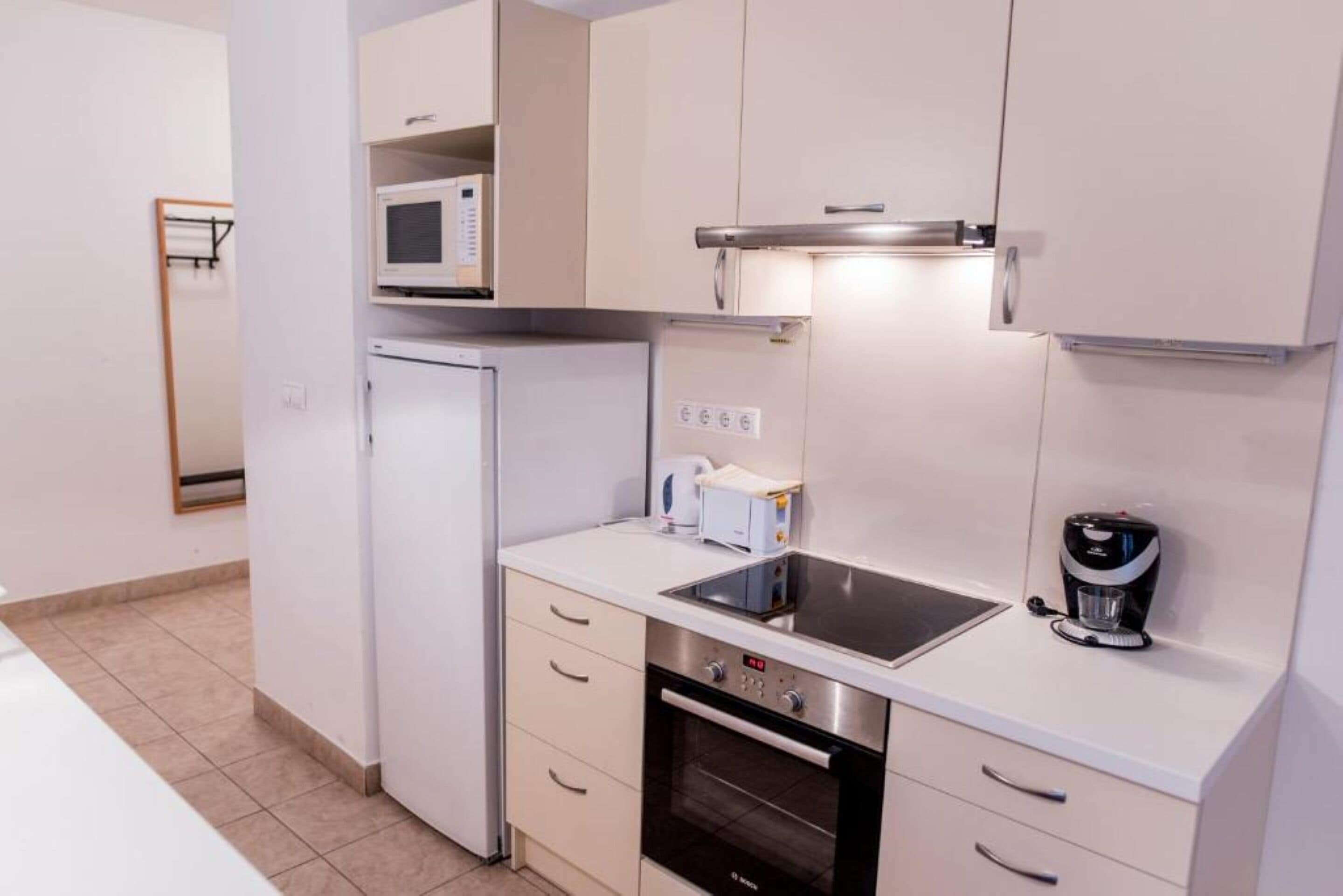 Eine kompakte Küche mit Mikrowelle, Toaster, Kaffeemaschine, Backofen und einem kleinen Spülbecken.