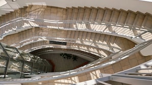 Eine moderne Wendeltreppe mit Glasgeländern und beige gestrichenen Wänden.