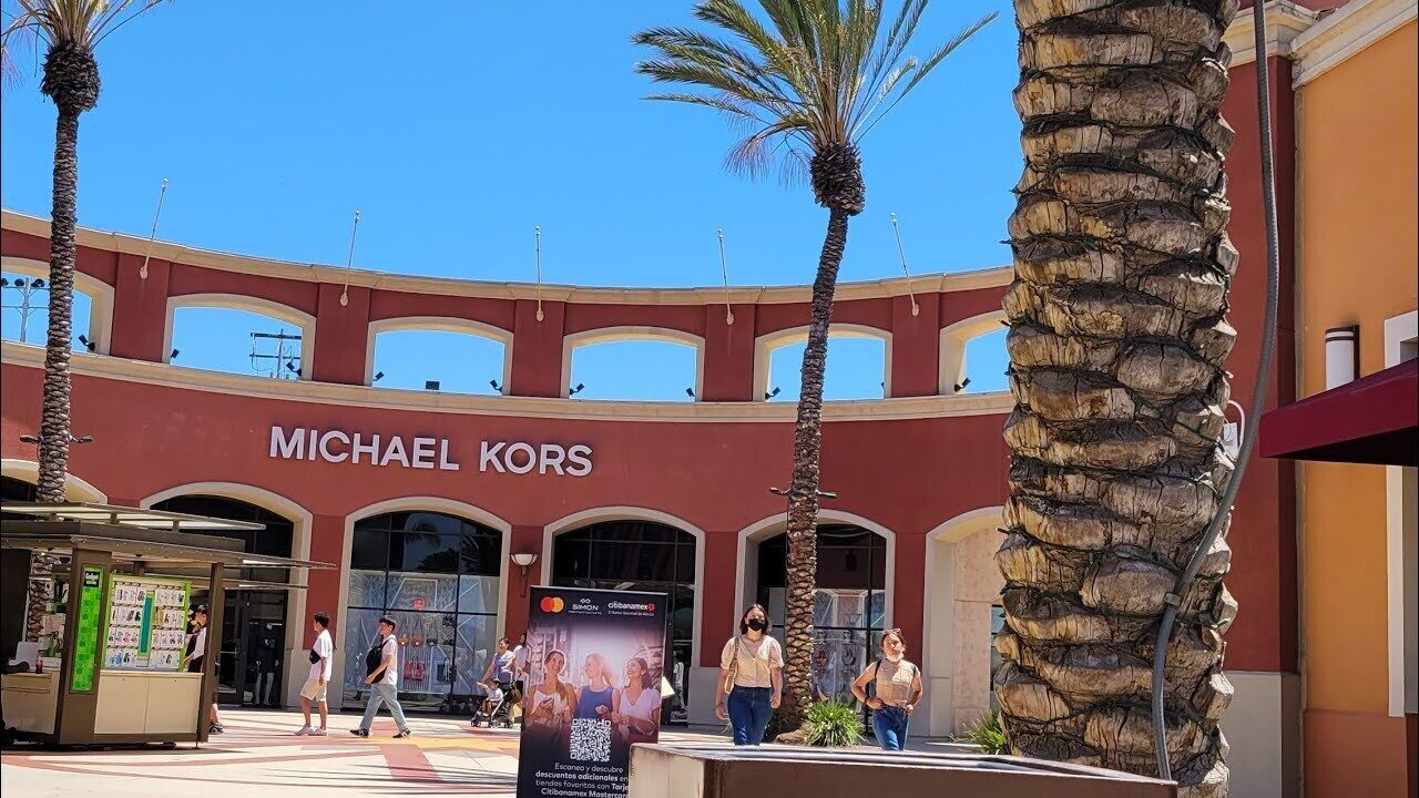 Una tienda Michael Kors con fachada roja y ventanas arqueadas.